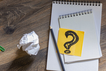 Idea concept, question mark on a sheet of paper with notepads and a pencil on a wooden table