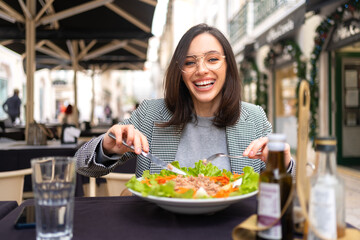 Business woman in glasses eating salad at cafe table