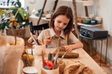 Working with clay. Little girl is learning how to do pottery in the workshop