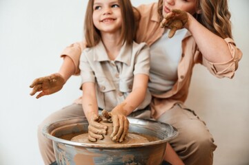 Making the pot out of clay. Mother with little girl doing pottery at home