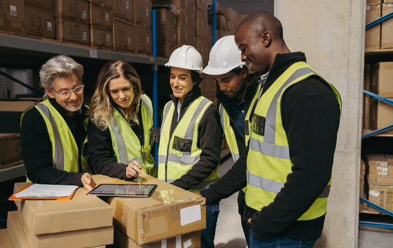 Cheerful warehouse team looking at a statistical report on a digital tablet