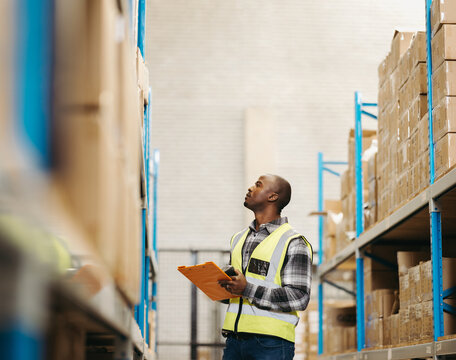 Young logistics worker taking stock in a modern warehouse