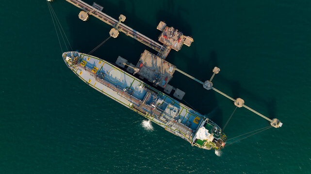 crude oil floating station in sea, bridge pipeline load unloading crude oil from oil ship transport, industry business transportation by container ship open sea, aerial drone point of view