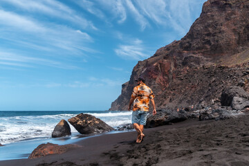 Fototapeta na wymiar Tourist on vacation on the black volcanic sand beach of Ingles in Valle Gran Rey on La Gomera, Canary Islands