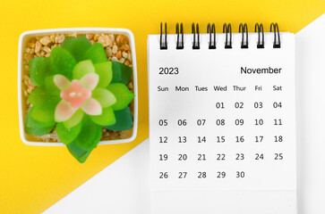 The November 2023 Monthly desk calendar for 2023 year with small tree on yellow background.