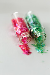 Two glass bottles pink and green glitter used for nail art designs
