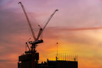 New construction site with crane and mechanical equipment on sunset background. Construction crane, industrial building