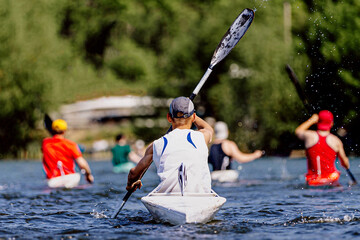 rear view group athletes kayakers on kayak single rowing on lake, summer outdoors sports