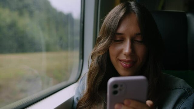 Close-up of the face of a young woman who is typing in a smartphone while traveling on a train