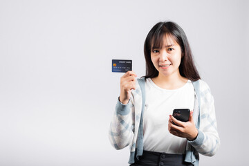 Naklejka premium Woman excited smiling hold mobile phone and plastic debit credit bank card for payment studio shot isolated white background, happy young female using smartphone buy and pay online shopping