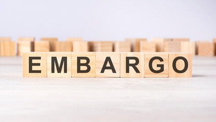 Fototapeta premium word EMBARGO inscribed on wooden cubes lying on a light table. economy and investments concept.