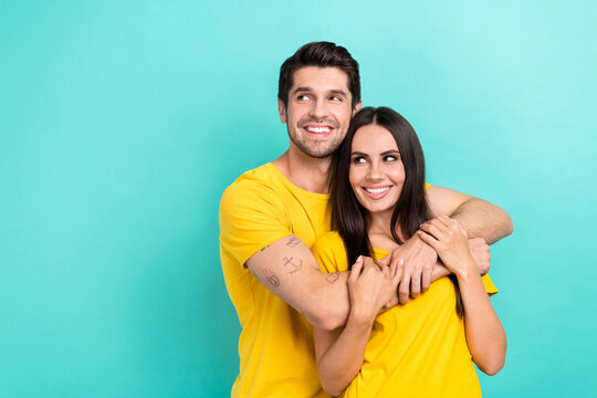 Photo of excited dreamy married couple wear yellow t-shirts cuddling looking empty space isolated teal color background