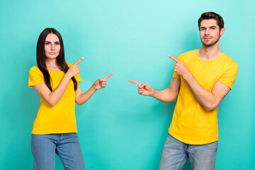 Photo of serious confident husband wife dressed yellow t-shirts showing fingers empty space isolated turquoise color background
