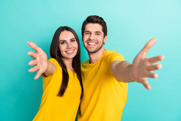 Photo of cheerful funny married couple wear yellow t-shirts hugging open arms isolated teal color...