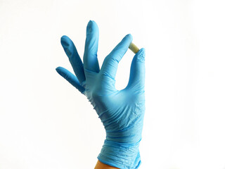 Hand in medical blue gloves holding one  pill isolated on white background