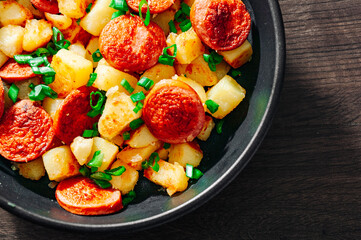 Roasted Potato and Sausage in frying pan on wooden table