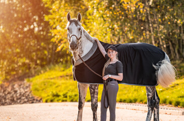 Young horse rider girl standing with her horse. Equestrian theme.