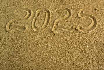 Fototapeta na wymiar The inscription 2025 on the sea sand. Beautiful holiday background.