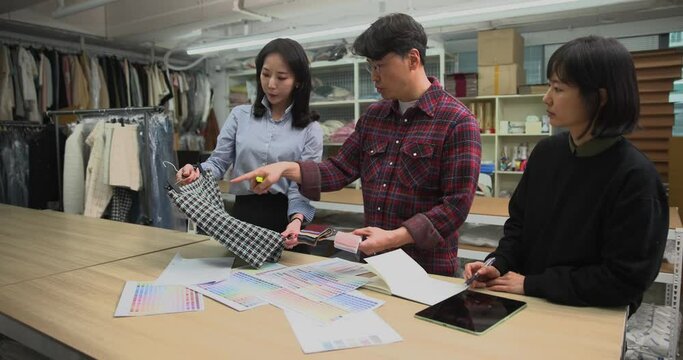 체크무늬 샘플바지와 스와치를 보면서 의상디자인 회의중인 디자이너들 