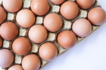 Fresh chicken brown eggs in a tray on a white background