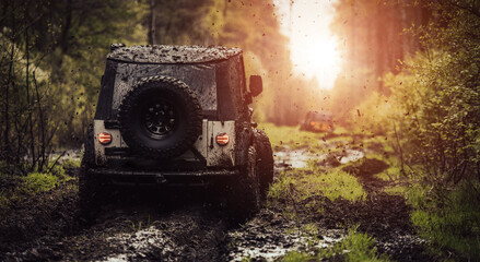 Offroad vehicle driving through the mud towards the setting sun. © peterzayda