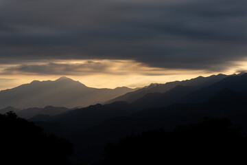 Fototapeta premium Layers of Mountains at Sunset with Silhouette and Dramatic Clouds