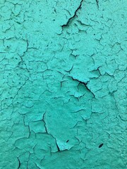 Concrete greeen and blue painted wall up close with some cracks 