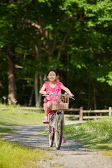 Naklejka premium 夏の公園で元気で自転車を乗って遊んでいる小学生の女の子の様子