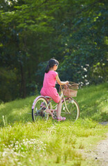Fototapeta premium 夏の公園で元気で自転車を乗って遊んでいる小学生の女の子の様子