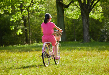 Obraz premium 夏の公園で元気で自転車を乗って遊んでいる小学生の女の子の様子