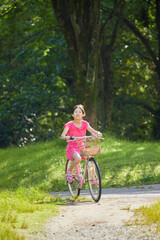 Naklejka premium 夏の公園で元気で自転車を乗って遊んでいる小学生の女の子の様子