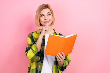 Portrait of pretty smart girl hand touch chin hold book look empty space contemplate isolated on pink color background
