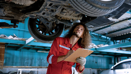 Man car mechanic Caucasian, was inspecting condition car that came into garage with some abnormal car symptoms, keep checkbook on vehicle before repairing it for quick fixes spotting any malfunctions.