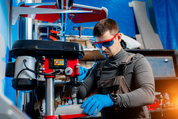 Young male engineer or technician using drill for drone details in lab. Aircraft capable of GPS surveillance. Carbon.