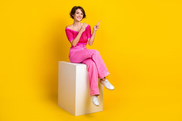 Fototapeta na wymiar Full length photo of gorgeous girl dressed knitwear top pink pants directing proposition empty space isolated on yellow color background