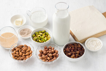 Ingredients for the traditional Arabic dessert Umm Ali: nuts, raisins, milk, cream, brown sugar, vanilla sugar, flour, butter and ready-made puff pastry on a light gray background