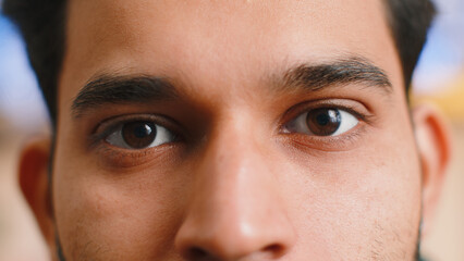 Extreme close-up macro portrait of smiling indian man face. Young guy eyes looking at camera. Adult...
