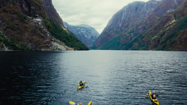 Three yellow kayaks paddle in epic beautiful fjord in Norway. Outdoors adventure. Active vacation and holiday in Scandinavia