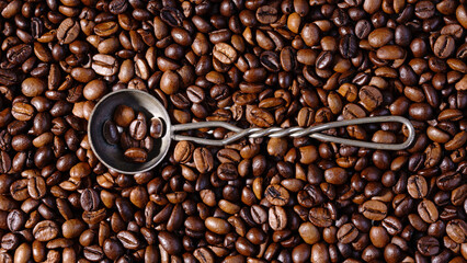 Palone ziarna kawy wypełniające tło z metalową łyżeczką