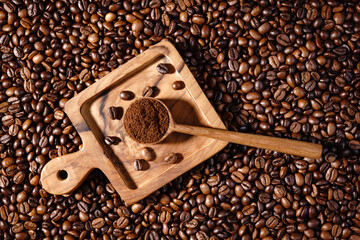 Palone ziarna kawy z drewnianym podstawkiem i łyżeczką z mieloną kawą