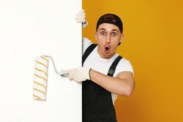 young man in working clothes painting white walls