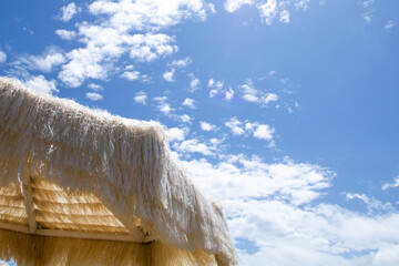 White straw umbrella on the beach against the sky