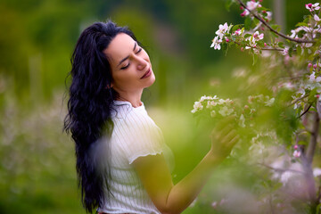 portrait of a beautiful brunette woman in a blossoming apple orchard