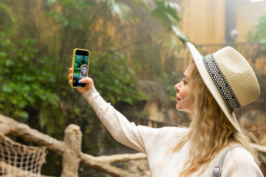 Woman taking selfie on phone in botanical garden 
