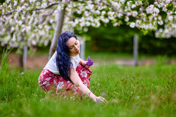 Fototapeta premium portrait of a beautiful brunette woman in a blossoming apple orchard