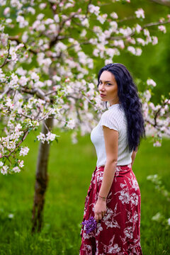 portrait of a beautiful brunette woman in a blossoming apple orchard