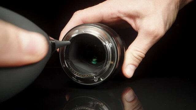 I blow the dust off the lens with a rubber Bulb on a black background. Dolly slider extreme close-up.
