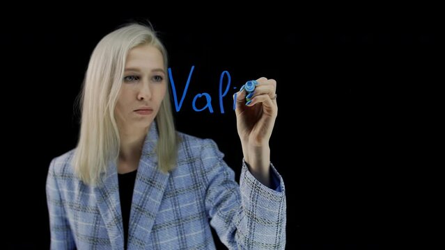 The word validators on a black background. A girl writes a word with a blue marker on a glass surface.