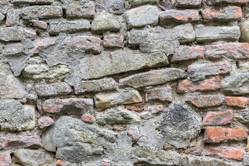 Old stone wall with irregular stones, cement has fallen down long time ago.