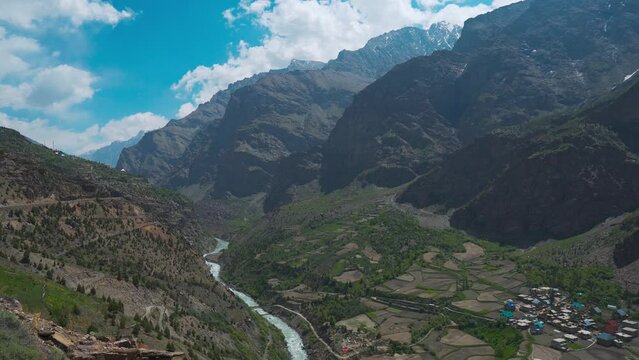 Beautiful 4k shot of Bhaga river flowing in mountain valley at Jispa in Lahaul, Himachal Pradesh, India. River, mountain, village houses and farms during summer. Tourism in Lahaul. Nature background. 